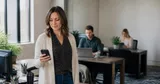 An office worker in a small Northeast Ohio office typing into an AI chat tool on a laptop while a coworker looks on