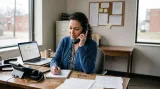 Office worker talking on a phone beside a laptop