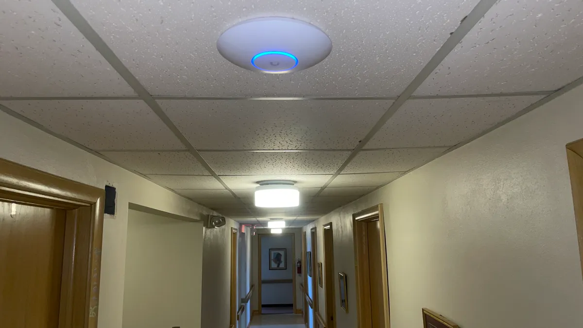 A ceiling-mounted wireless access point above a hallway A ceiling-mounted wireless access point above a hallway