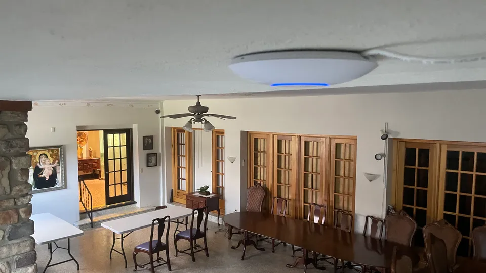 A ceiling-mounted wireless access point above a monastery gathering room A ceiling-mounted wireless access point above a monastery gathering room