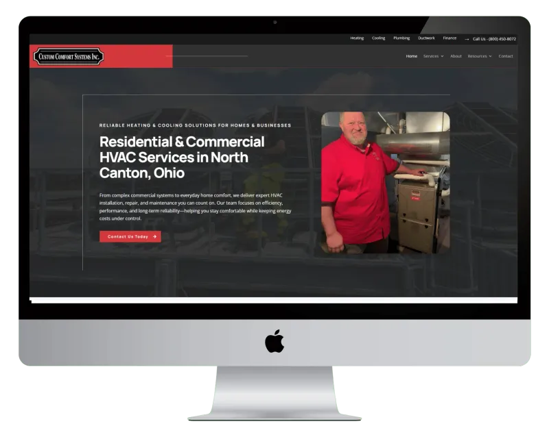 Custom Comfort Systems homepage on a desktop monitor, with a man in a red shirt standing beside a furnace Custom Comfort Systems homepage on a desktop monitor, with a man in a red shirt standing beside a furnace