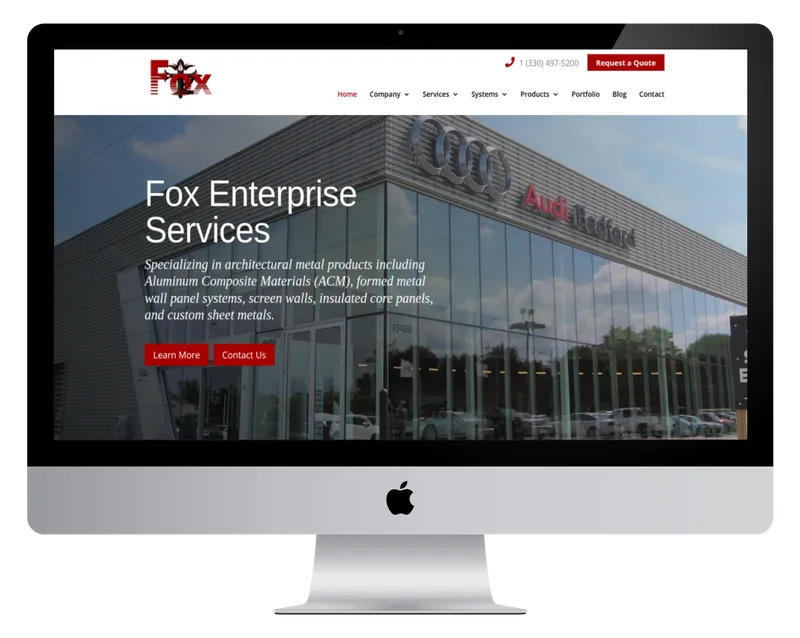 Fox Enterprise Services homepage on a desktop monitor, with a metal-panel and glass commercial building Fox Enterprise Services homepage on a desktop monitor, with a metal-panel and glass commercial building