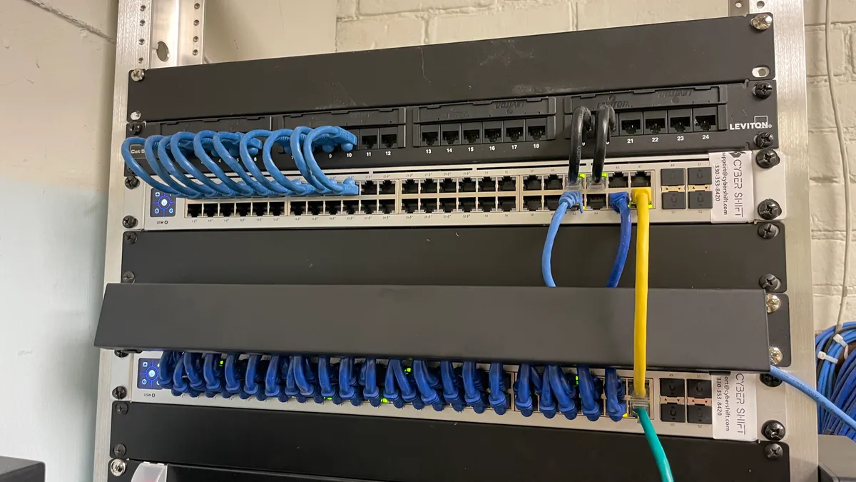 Installed network switches and patch panels with blue cables and Cyber Shift support labels Installed network switches and patch panels with blue cables and Cyber Shift support labels