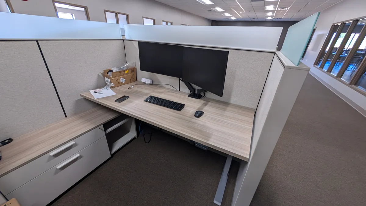 An office workstation with two monitors, a keyboard and a mouse in a cubicle An office workstation with two monitors, a keyboard and a mouse in a cubicle