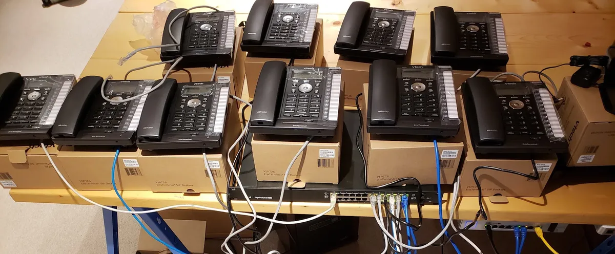 Desk phones connected to a network switch on a workbench