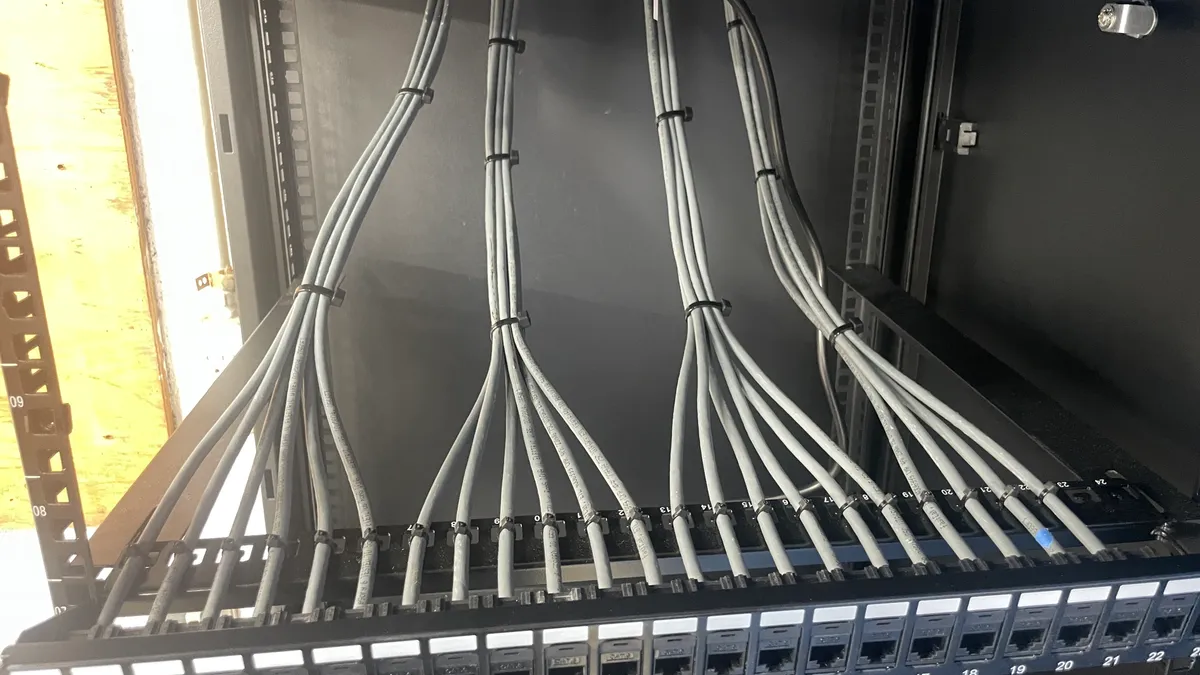 Network cables routed into a patch panel inside a wall-mounted cabinet Network cables routed into a patch panel inside a wall-mounted cabinet