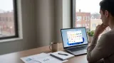 Person using a laptop at a desk beside an office window